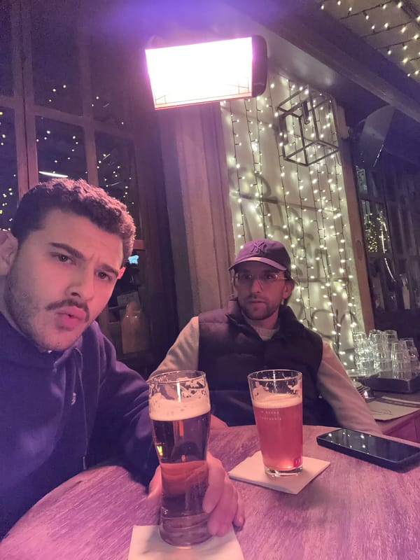 Two men share beers at table in Milan