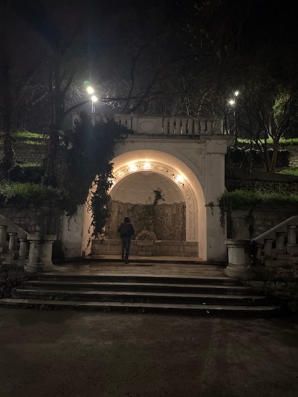 Person stands by illuminated historic architecture in Varna
