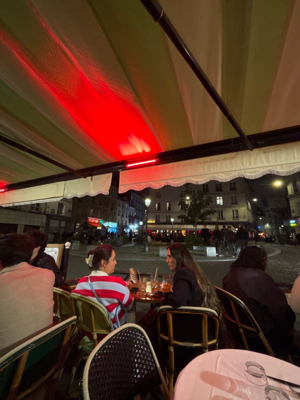 Parisians dine al fresco under striped awnings on spring evening