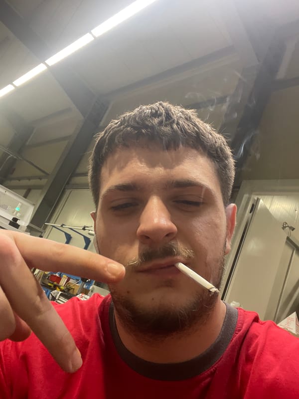 Man smoking indoors makes peace sign in Bulgarian industrial setting