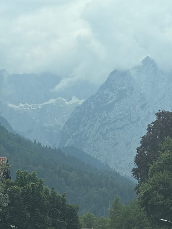 Misty mountain range seen from roadside, clouds heavy on peaks