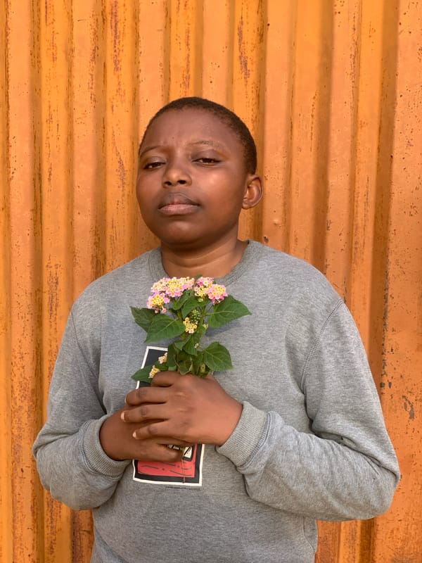 Person with flowers observed resting against wall in Ikorodu