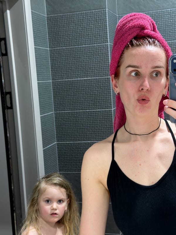 Woman takes bathroom selfie with child visible in mirror