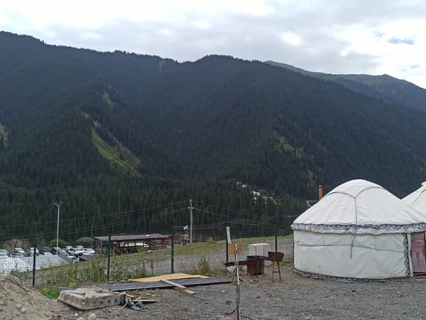 Yurt camp nestled below forested mountains in Kurmeti, Kazakhstan