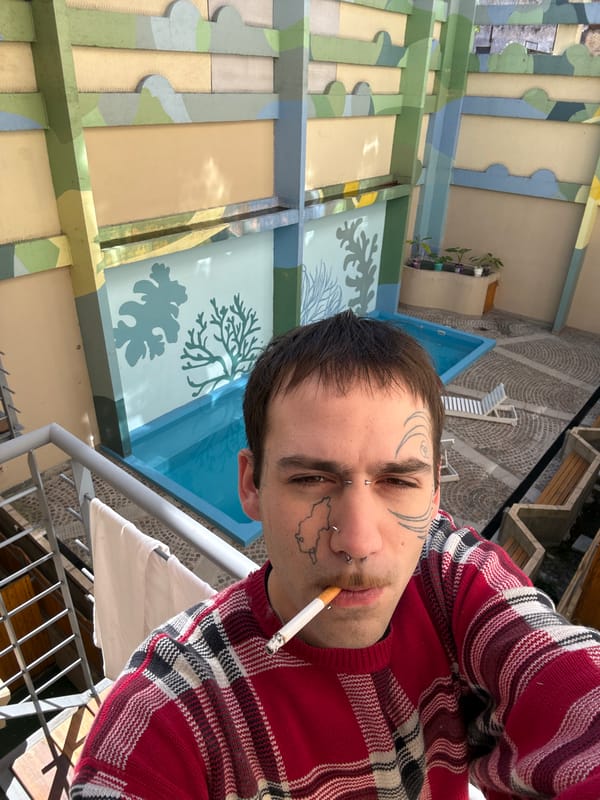 Tattooed person smoking, cat resting on Buenos Aires balcony