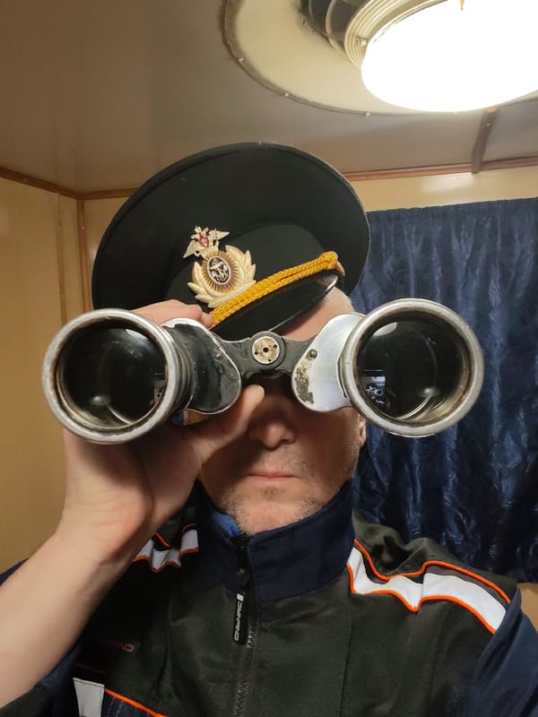 Man with uniform cap uses vintage binoculars in Rybinsk