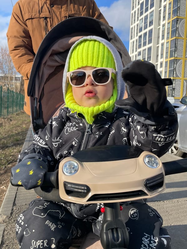 Child enjoys ride-on toy outdoors in sunny Izhevsk