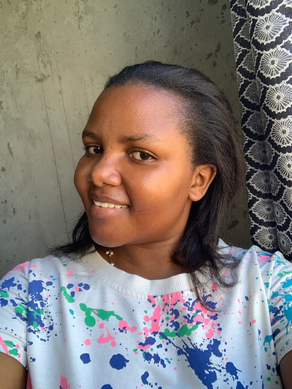 Woman in paint-splattered shirt photographed smiling in Dar es Salaam