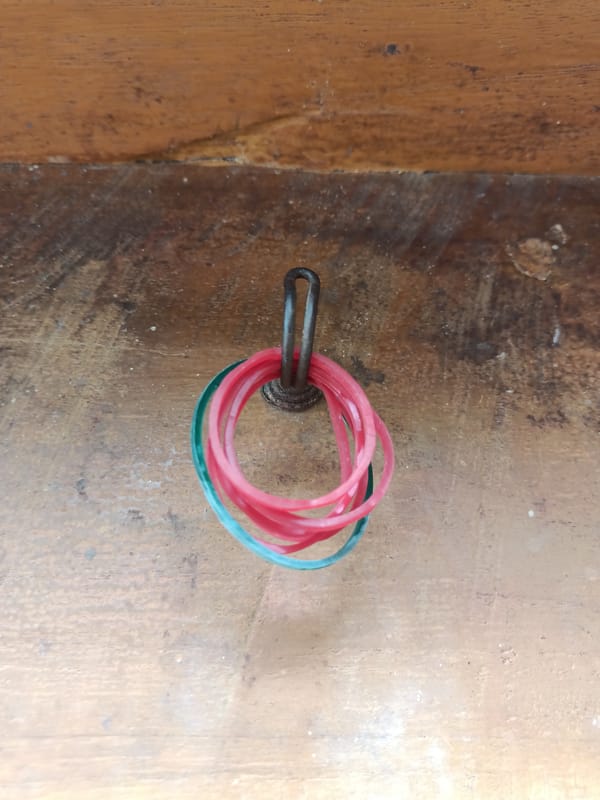 Two cats nap on concrete beside a rubber band hook
