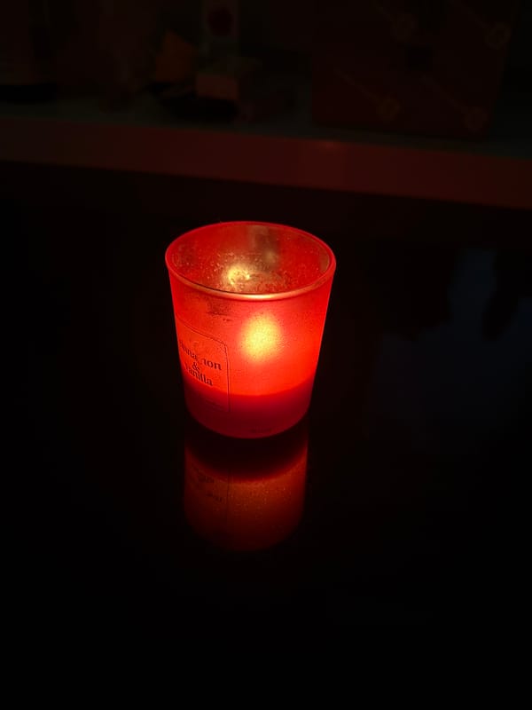 Red votive candle glowing on a dark countertop at home