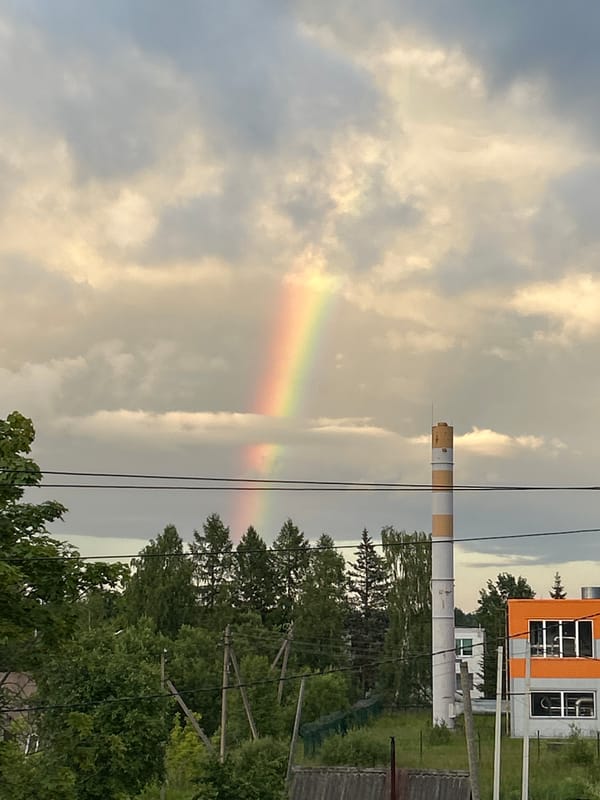 Rainbow over a striped industrial chimney in rural Russia