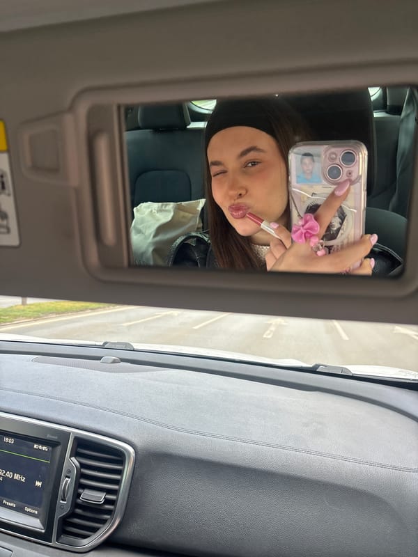 Woman Takes Selfie While Applying Makeup in Car Mirror