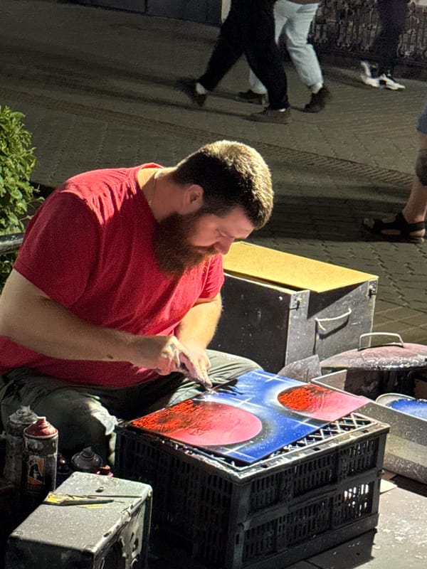 Street artist spray paints and displays work outdoors in Kazan