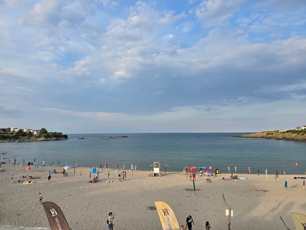 Crowded beach, evening event, and solo fishing near rocky shore
