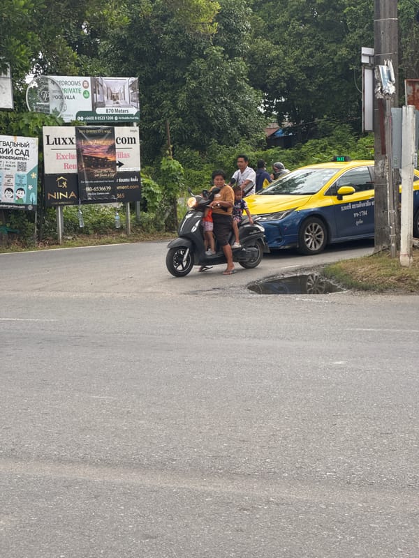 Motorcycles gather on Chalong road with delivery rider present