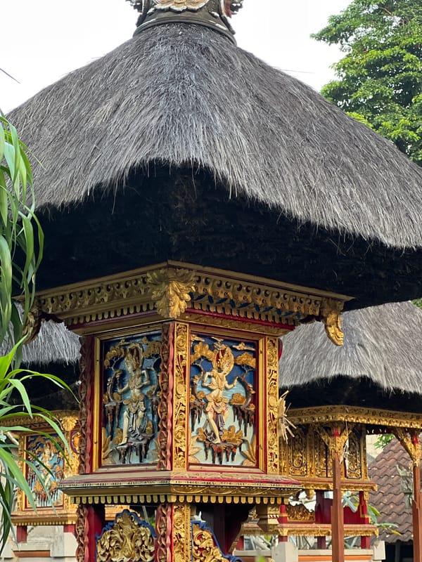 Cat rests on stone ledge near traditional architecture in Ubud