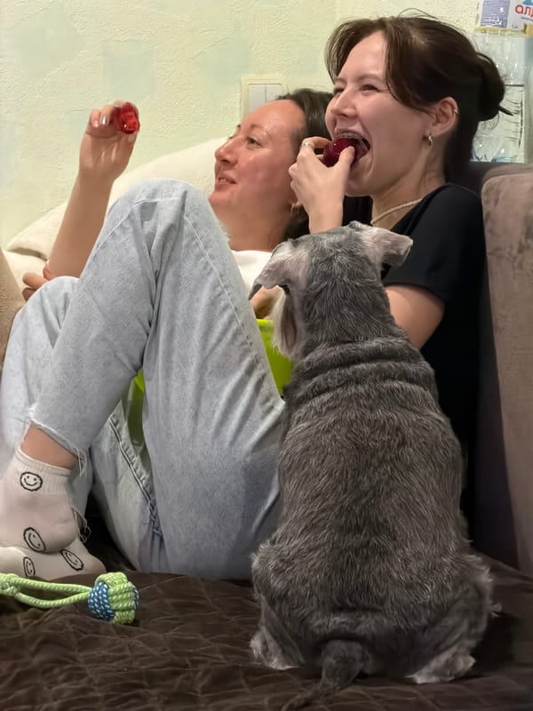 Women share fruit on couch with pets in Chaikovsky