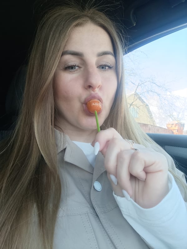 Woman eating orange lollipop while sitting in car