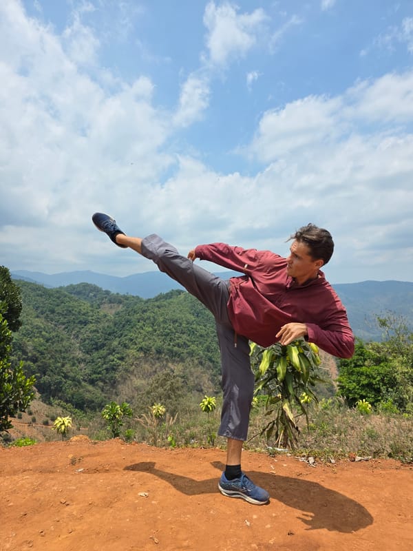 Man performs martial arts kicks on mountain overlook in Vietnam