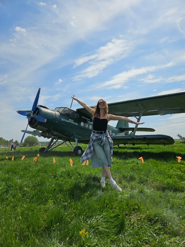 Woman poses with vintage biplane at outdoor event in Izhevsk