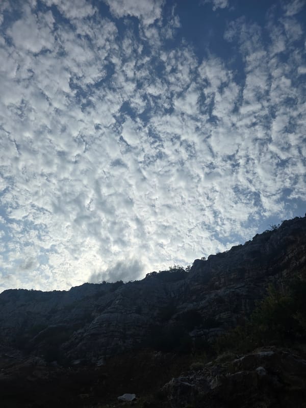 Rocky mountain ridge under scattered clouds, possible quarry site nearby