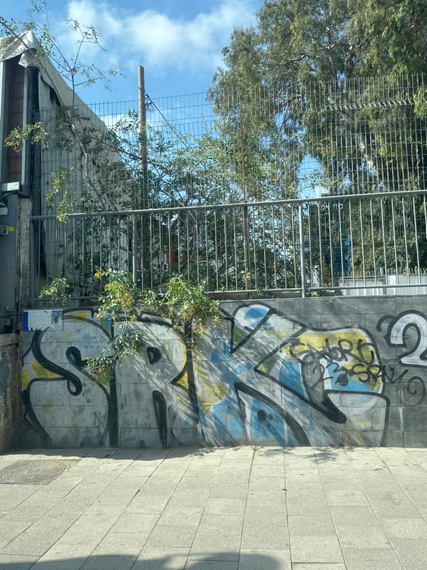 Graffiti wall and shuttered kiosk on a Tel Aviv sidewalk