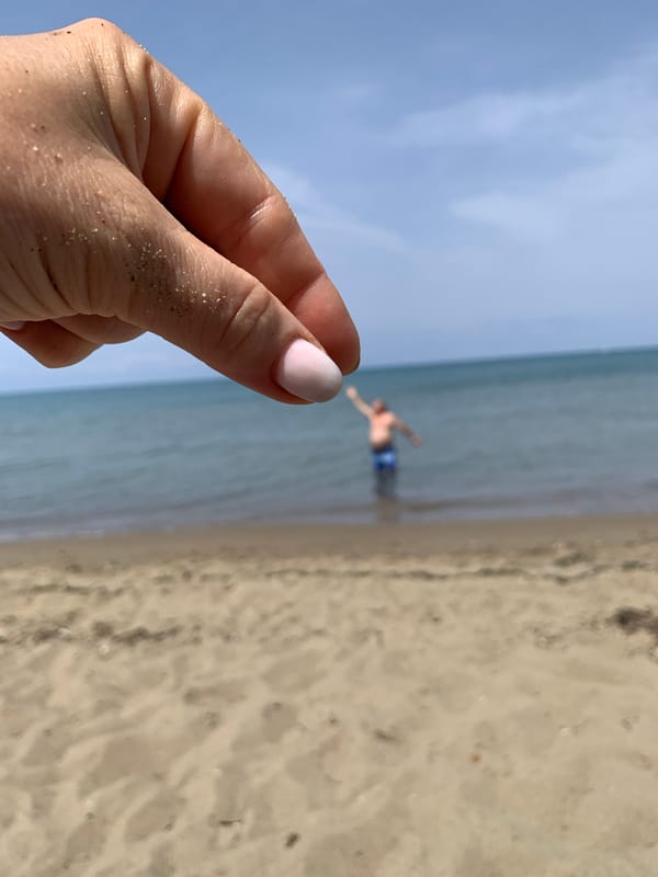 Sand-dusted hand at an Italian beach, summer detail