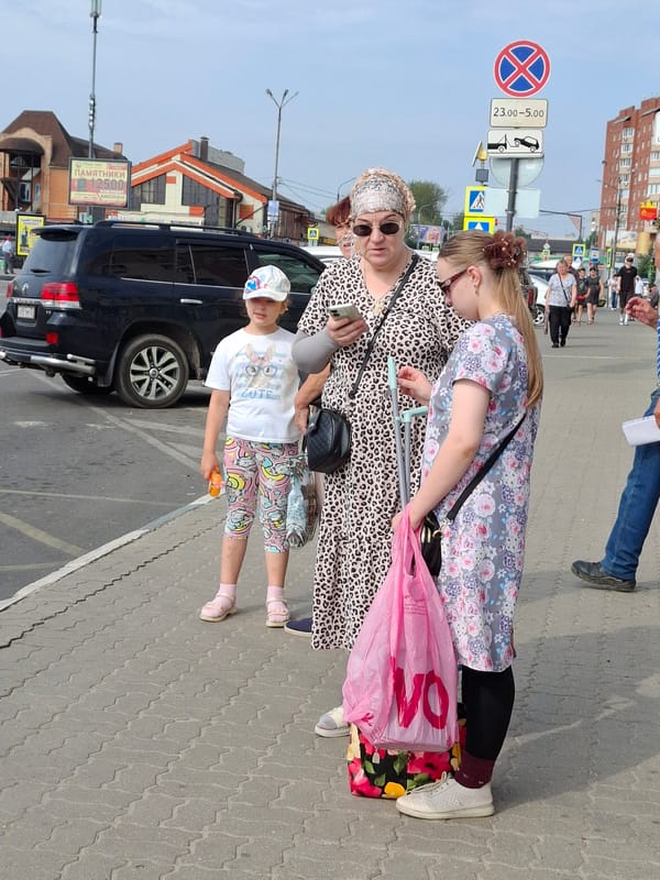 Sidewalk life: pedestrians, an outdoor market, and blooming flowers