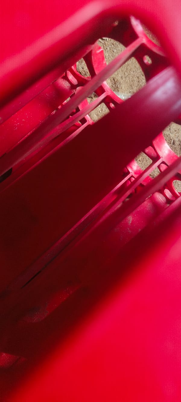Red plastic crate spotted on sandy ground in Sapele