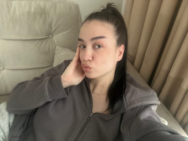 Woman in grey hoodie poses on sofa in Sofia