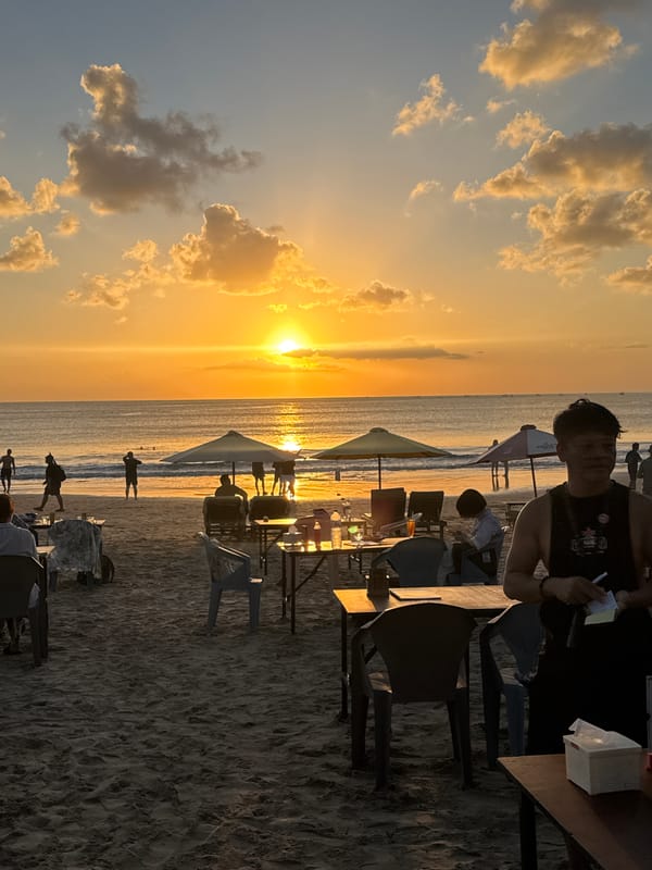 Golden hour on Kuta Beach with planes, waves, and beachgoers