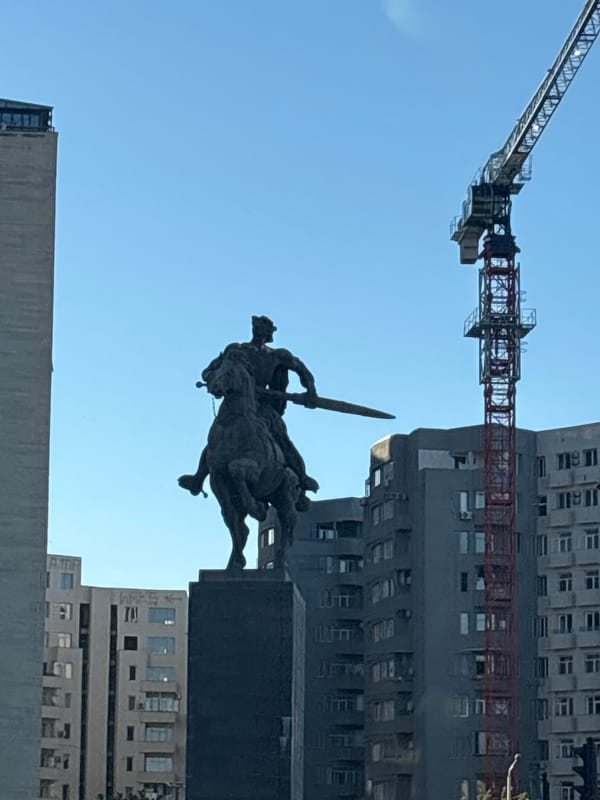 Warrior statue observed in busy Tbilisi street scene