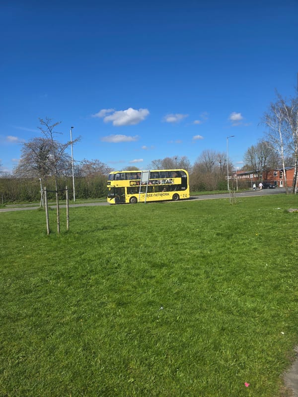 Yellow Bee Network bus travels Manchester road on spring day