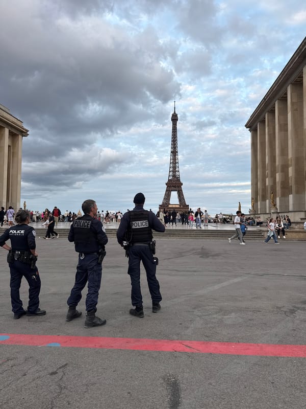 Evening crowds and police patrol near Eiffel Tower