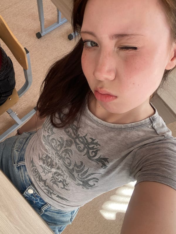Woman takes winking selfies in gray shirt and denim