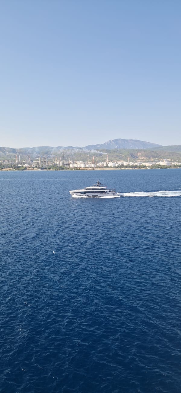 Luxury yacht passes industrial coastline near Agioi Theodoroi