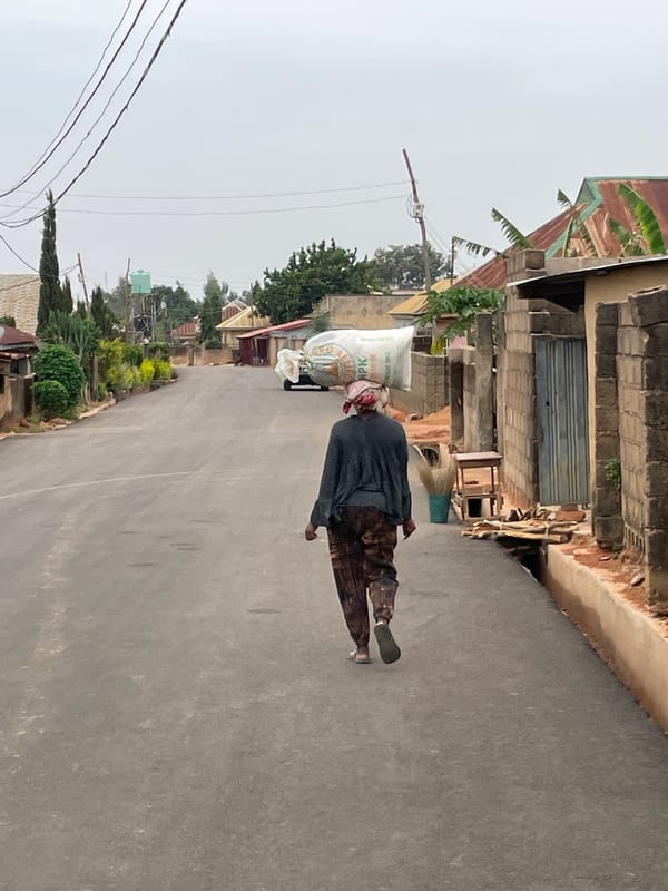 Person carries large sack while walking road in Jos