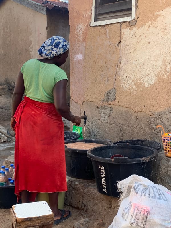 Woman transfers water using scoop near plastic tubs