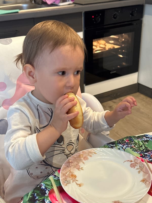 Toddler chef bakes in kitchen wearing hat, whisking batter