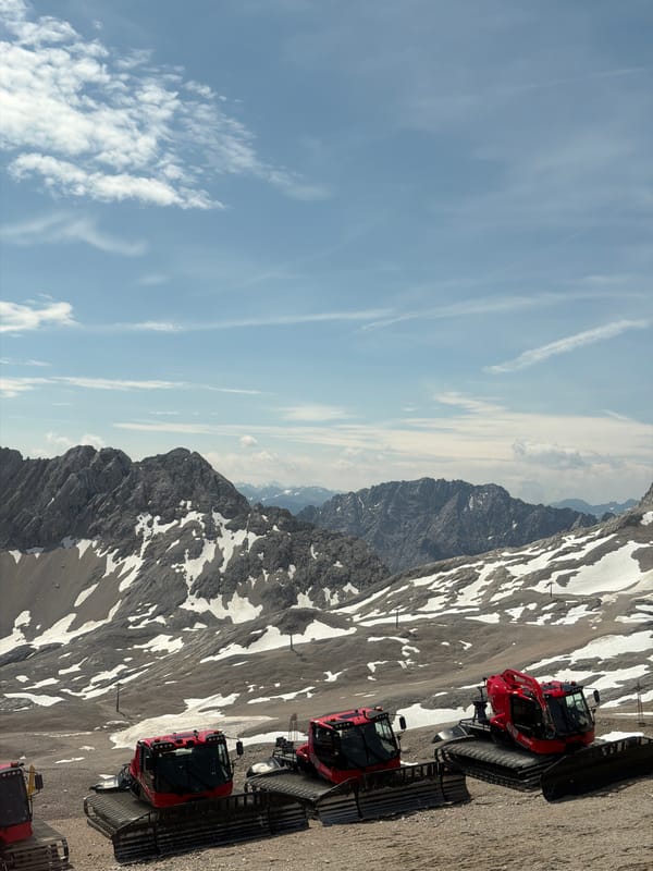 Snow groomers parked on a rocky Alpine summit in summer