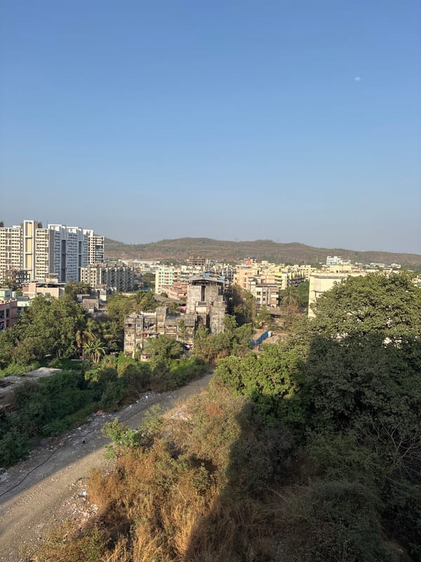 Daytime crescent moon visible over Ambernath hillside town