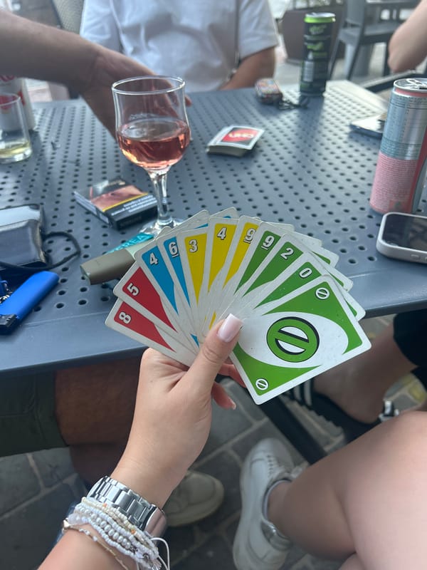 Friends play UNO cards at outdoor Malta café