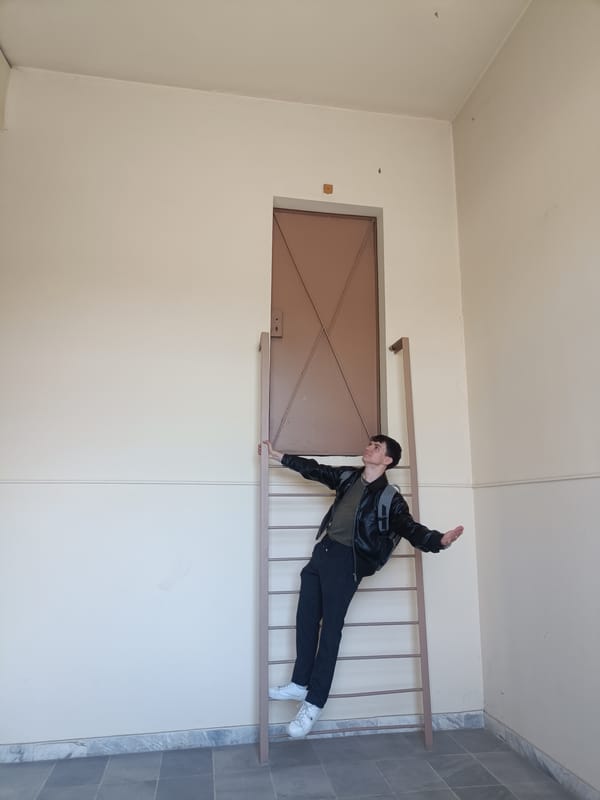Young man strikes whimsical pose on ladder indoors