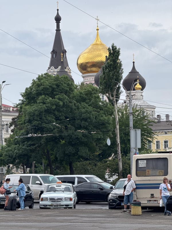 Group gathered near vehicles, church domes visible in urban background