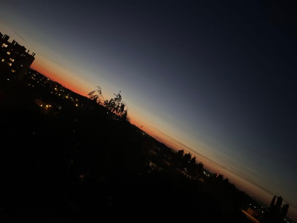 City skyline at dusk, sunset sky and crescent moon