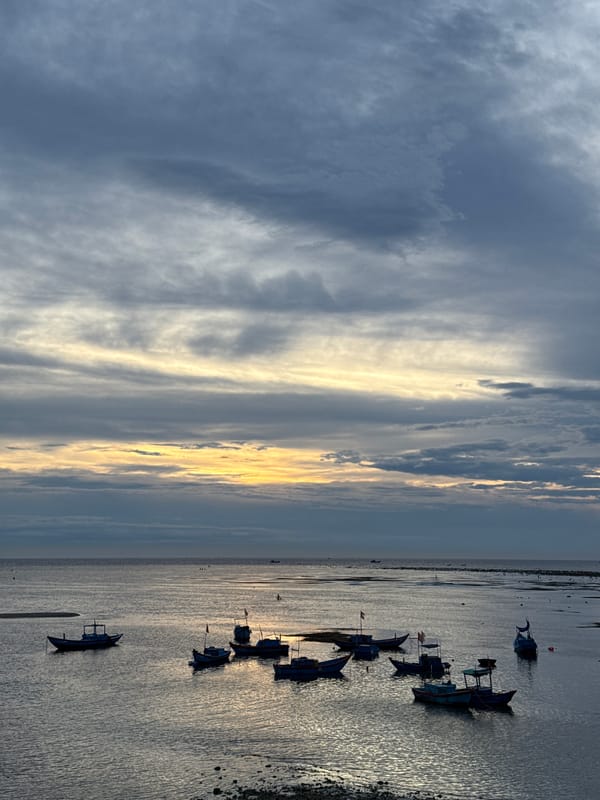 Lý Sơn Island at dusk: boats, paddlers, and a rising moon