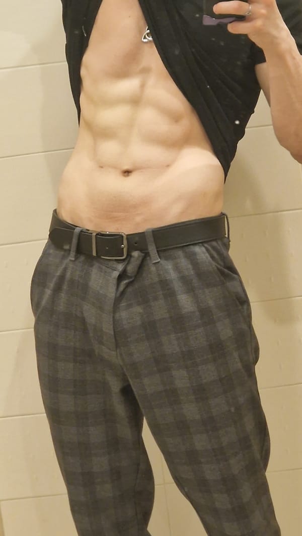 Person poses with exposed torso in tiled indoor space