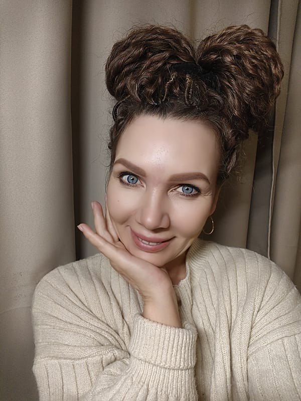 Woman poses for photos in cream sweater and double buns