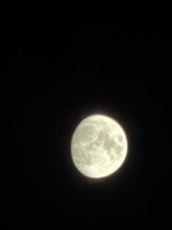 Full moon night over a city skyline with a Qatar Airways flight