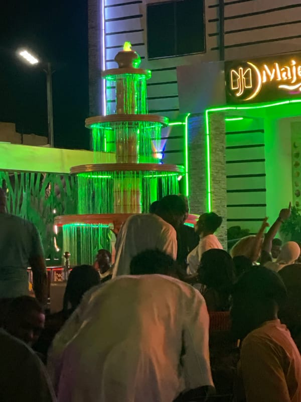Evening crowd gathers at illuminated Majestic Lounge in Tumfure